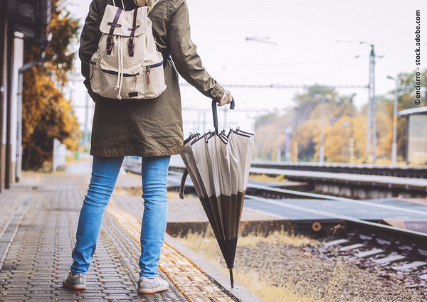 Frau mit Regenschirm am Bahnsteig