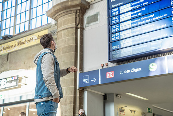 Ein Mann steht vor einer Anzeigentafel im Bahnhof Hagen