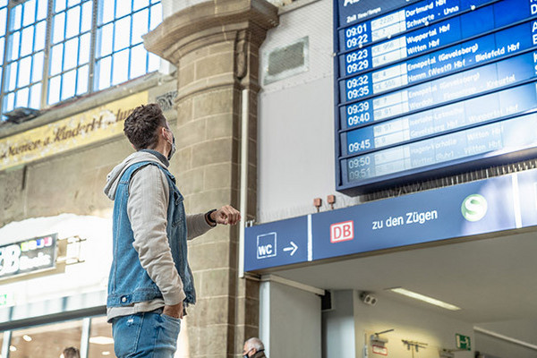 Ein Mann steht vor einer Anzeigentafel im Bahnhof Hagen